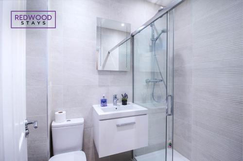 y baño con aseo, ducha y lavamanos. en 2 Bedroom 1 Bathroom Town Center Apartment With FREE Parking By REDWOOD STAYS, en Basingstoke