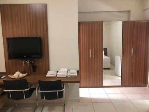 Zimmer mit einem Schreibtisch mit Stühlen und einem Spiegel in der Unterkunft Paracatu Plaza Hotel in Paracatu