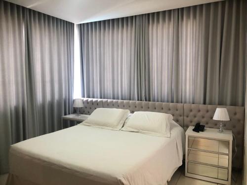 um quarto com uma grande cama branca e uma janela em Paracatu Plaza Hotel em Paracatu