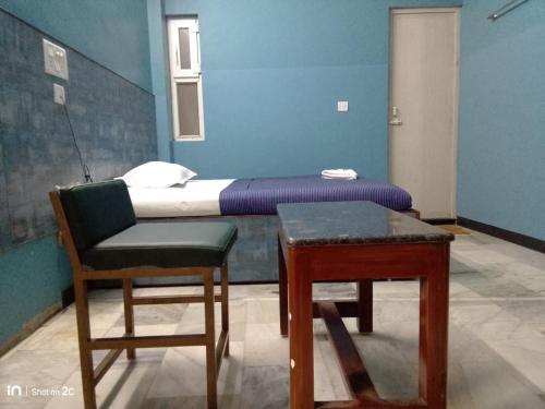 a room with a bed and a chair and a table at SM MANSION near Harbour & High court in Chennai
