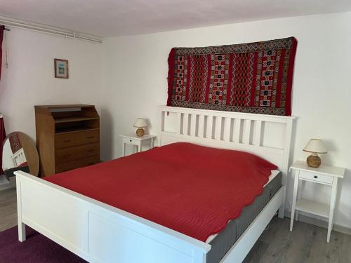 a bedroom with a white bed with a red bedspread at La chaumière aux fleurs in Saint-Paul-en-Chablais