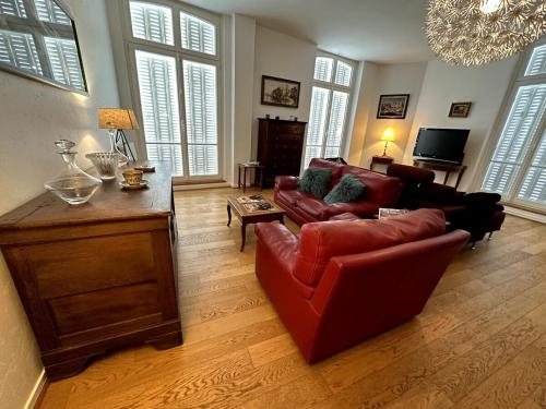 - un salon avec un canapé rouge et un fauteuil rouge dans l'établissement Le Grand Rockefeller Parvis de la Cathédrale de Reims, à Reims