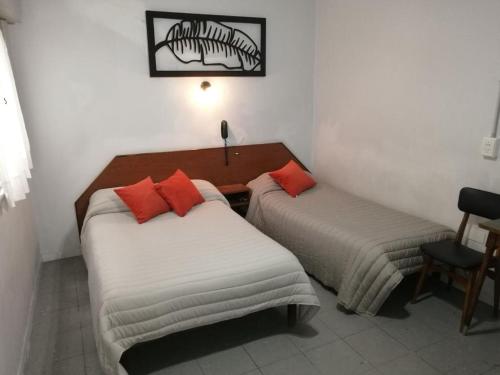 two beds in a hotel room with red pillows at Suite en Hotel Omega Palermo in Buenos Aires