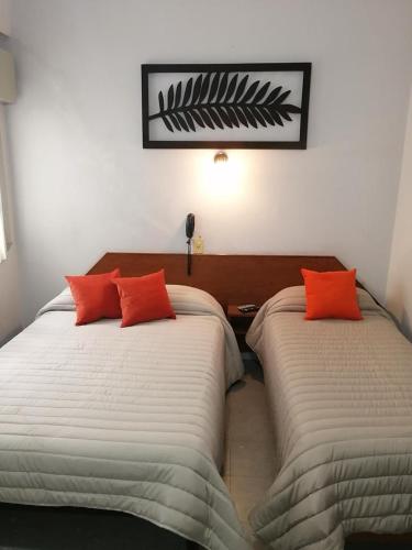 two beds with orange pillows in a room at Suite en Hotel Omega Palermo in Buenos Aires