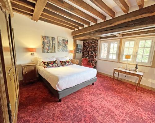 a bedroom with a large bed and a red carpet at Moulin de Fourges in Fourges