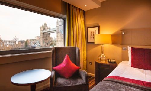 a hotel room with a bed and a chair and a window at The Tower Hotel, London in London