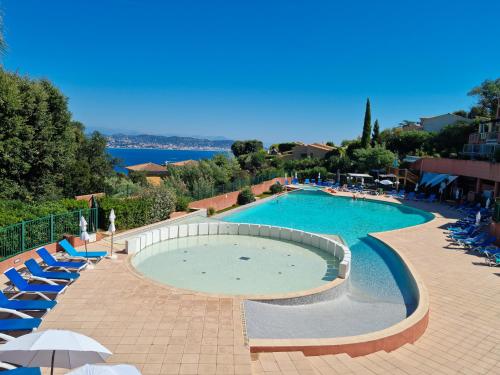 une grande piscine avec des chaises et des parasols bleus dans l'établissement Ravissant T2 vue mer et massif - Les Clés de L´Estérel, à Théoule-sur-Mer