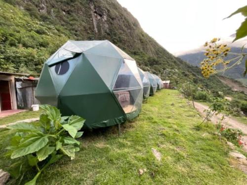 une rangée de tentes sur le côté d'une montagne dans l'établissement Sky Lodge Domes Chaullay, à Colcapampa