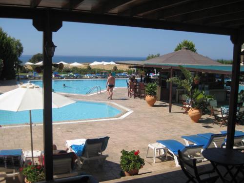 a swimming pool with chairs and a person walking by it at Akamanthea Holiday Village in Polis Chrysochous