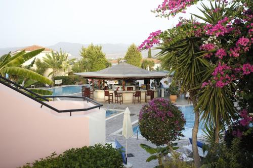 a resort with a pool and a restaurant with pink flowers at Akamanthea Holiday Village in Polis Chrysochous