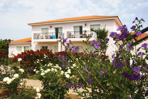 a white house with flowers in front of it at Akamanthea Holiday Village in Polis Chrysochous