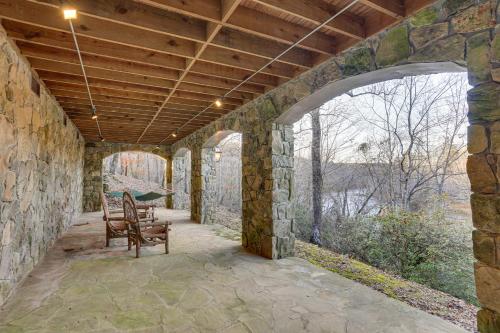 an outdoor patio with a stone wall and two chairs at Lakefront Custom-Built Mentone Home Game Room! in Mentone