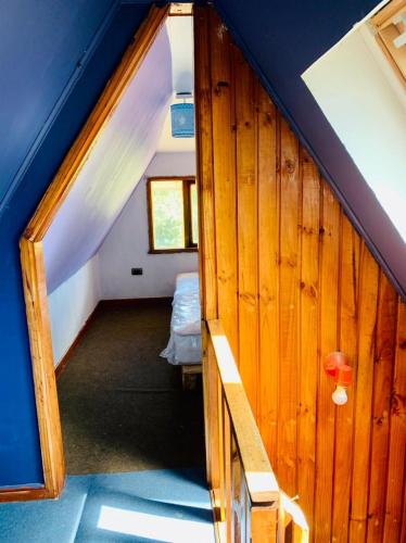 a small attic room with a bed and a blue ceiling at Cabañas El Trébol, a 5 minutos del aeropuerto in Puerto Montt