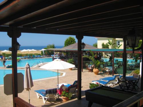 a view of a pool with chairs and an umbrella at Akamanthea Holiday Village in Polis Chrysochous