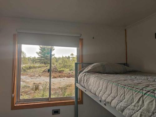 a bedroom with a bed and a large window at Cabañas El Trébol, a 5 minutos del aeropuerto in Puerto Montt
