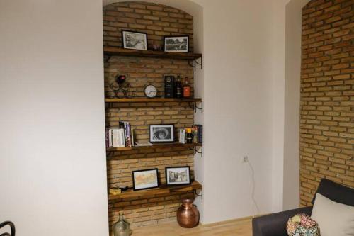 un mur en briques avec des photos encadrées sur une étagère dans l'établissement Anna's cosy home in Abanotubani, à Tbilissi