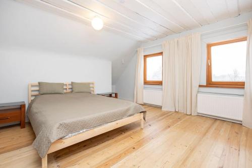 TuraidaにあるNice holiday home in Turaidaの白いベッドルーム(ベッド1台、窓2つ付)