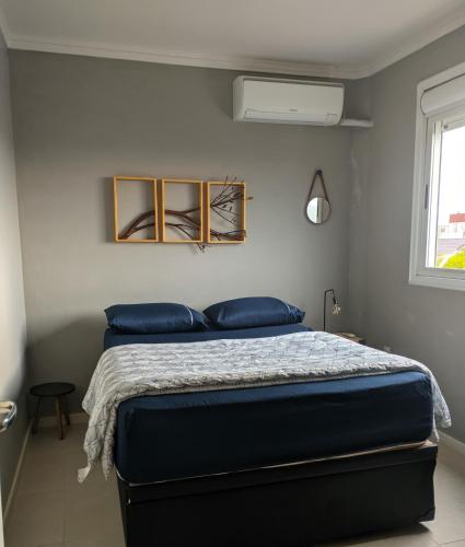 una camera da letto con un letto con cuscini blu e una finestra di Cantinho Estilo a Santa Maria