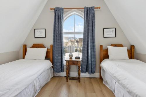 Cette chambre mansardée comprend 2 lits et une fenêtre. dans l'établissement 3BR Snowbridge Chalet in Blue with Golf Course View, à Collingwood