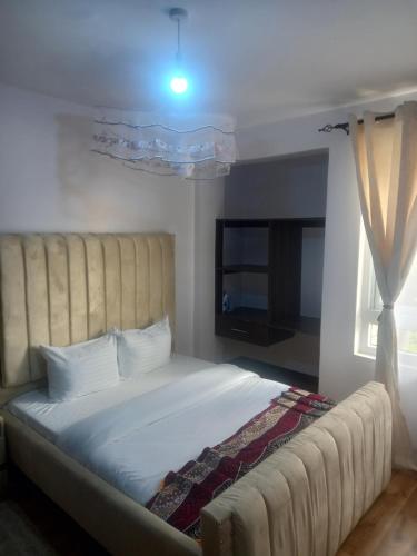 um quarto com uma cama grande e uma grande cabeceira. em THE G2 em Nakuru