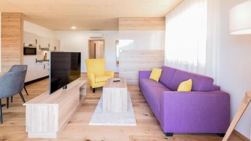 a living room with a purple couch and yellow chairs at Seewirt Apartments in Klopein am Klopeiner See
