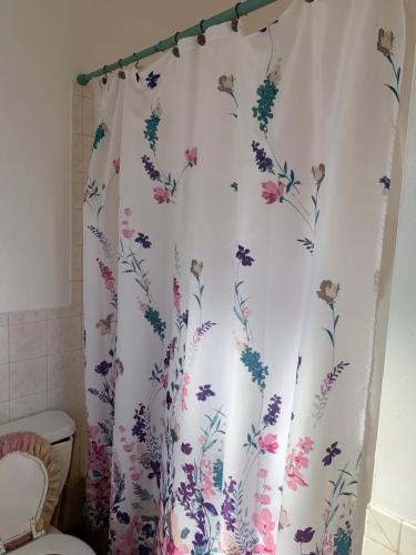 a shower curtain with a floral pattern on it in a bathroom at Bangaly Guest House Newyork in Locust Manor