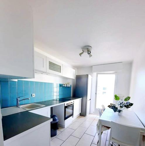 une cuisine avec des placards bleus et blancs et une table dans l'établissement Logement dans résidence - à 10 km du centre ville et à 5 minute du parlement européen avec parking gratuit, à Hoenheim