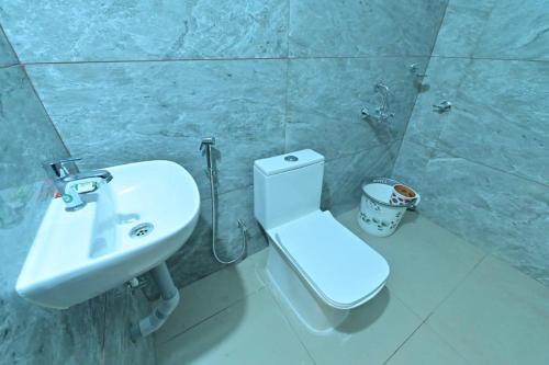 a bathroom with a white toilet and a sink at Gokula Homestay in Subrahmanya