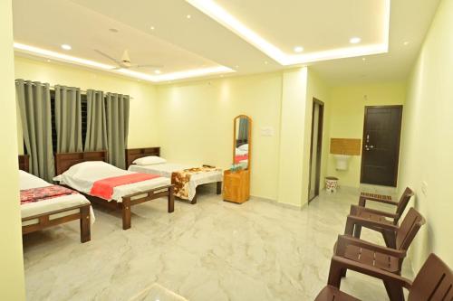 um quarto de hotel com duas camas e uma televisão em Gokula Homestay em Subrahmanya