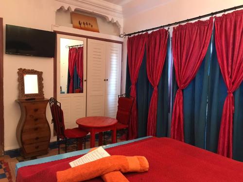 - une chambre avec des rideaux rouges et bleus et une table dans l'établissement Hôtel Riad Gnaoua, à Essaouira