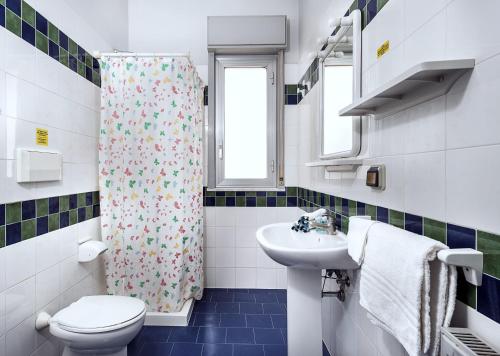 Un baño con lavabo e inodoro y cortina de ducha. en Villa Collina, en Giardini Naxos
