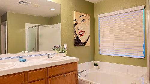 ein Badezimmer mit einem Waschbecken, einer Badewanne und einem Spiegel in der Unterkunft Spacious home sleeps 14 with pool table in Las Vegas