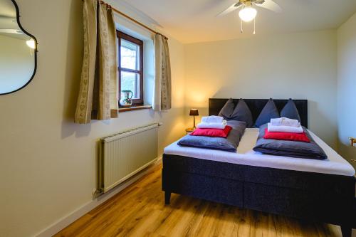 a bedroom with a bed with red and blue pillows at Landhaus BERGSEE in Bodensdorf