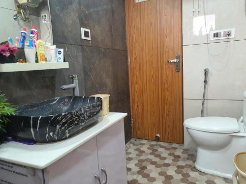 La salle de bains est pourvue d'un lavabo et de toilettes. dans l'établissement Lilac room,, à Faridabad
