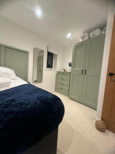 Schlafzimmer mit einem blauen Bett und grünen Schränken in der Unterkunft Modern 1 Bedroom House in Biggleswade in Biggleswade