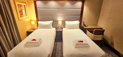Dos camas en una habitación de hotel con rosas rojas. en Hyde Park International, en Londres
