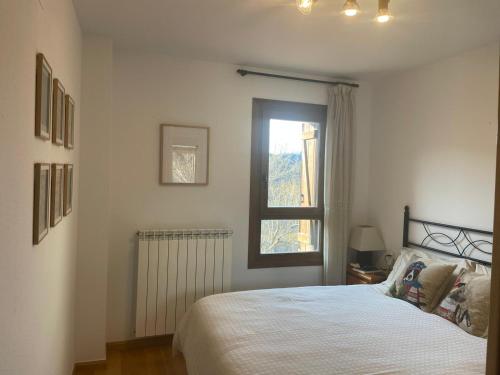 a white bedroom with a bed and a window at Inmocyma Cerler- Aigualluts-Pirineo en familia in Cerler