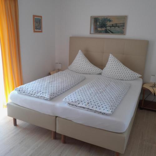 a bed with white sheets and pillows in a room at Pension Sedlak in Millstatt