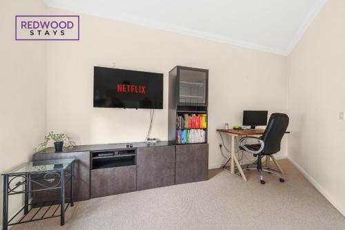 um escritório com uma secretária e uma televisão na parede em 2 Bedroom Apartment, Business & Contractors, FREE Parking & Netflix By REDWOOD STAYS em Basingstoke
