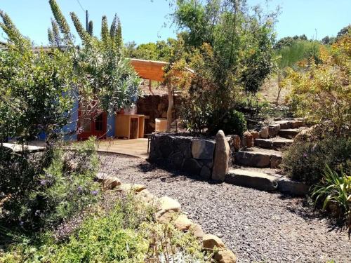 einen Garten mit Felsen und Bäumen und ein Haus in der Unterkunft Finca Caboquitos in Garafía