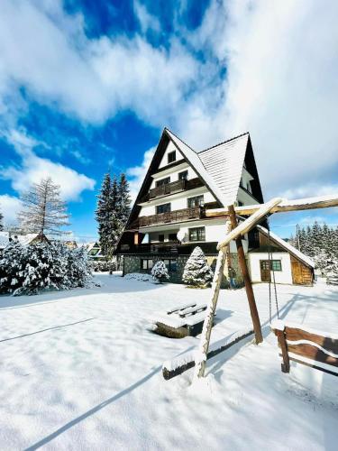 a large building in the snow with a bench at Willa Maria in Kościelisko