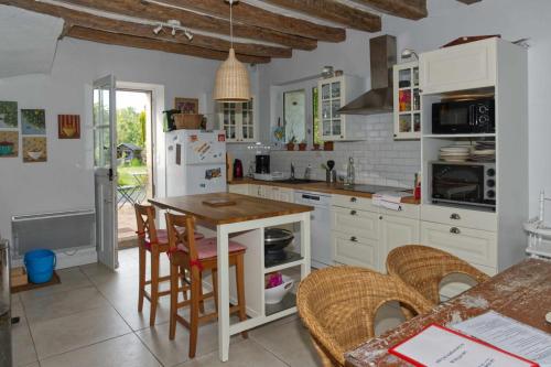 La belle de Ronsard في Chédigny: مطبخ مع دواليب بيضاء وطاولة وكراسي