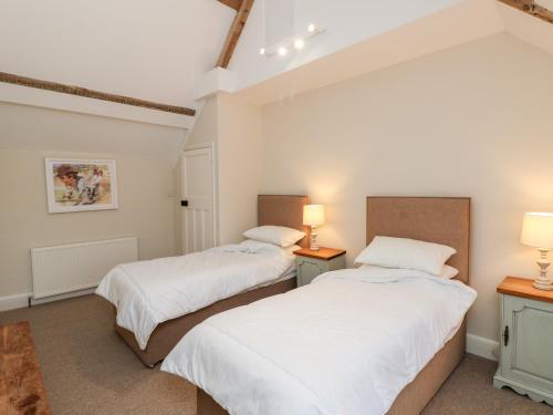 two beds in a room with white walls and two lamps at Appuldurcombe Farmhouse in Ventnor