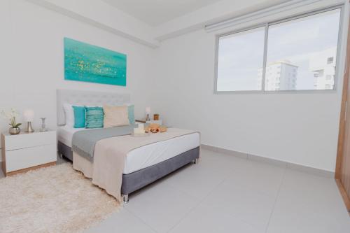 1 dormitorio blanco con 2 camas y ventana en Apartamentos Ambar Roca - Cerca al Mar by SOHO, en Santa Marta