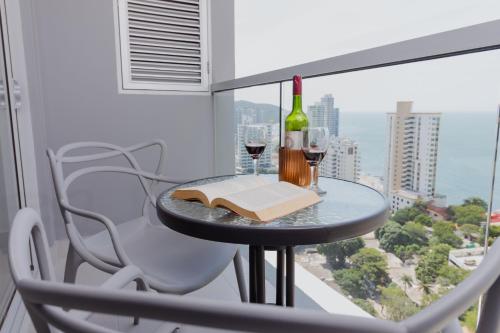 una mesa con copas de vino y un libro en el balcón en Apartamentos Ambar Roca - Cerca al Mar by SOHO, en Santa Marta
