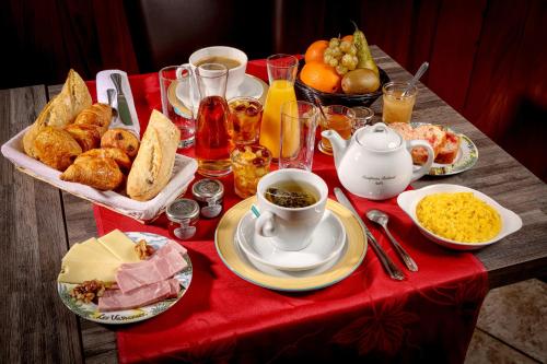 a table with breakfast foods on a red table cloth at Logis Hôtel-Restaurant Les Voyageurs in La Coquille