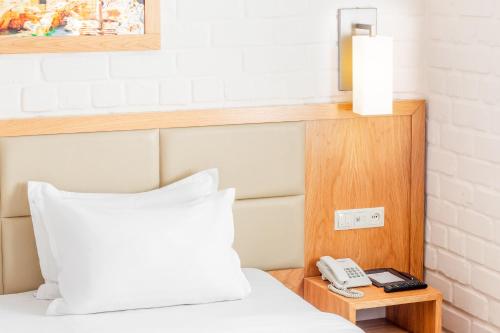 a bed with a white pillow and a telephone at Praga Hotel in Tashkent