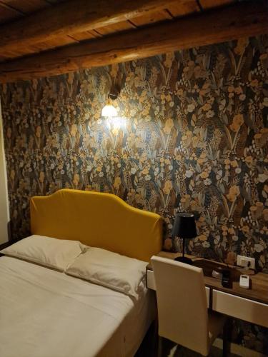 a bed with a yellow headboard and a desk at Locanda Al Centrale in Caprino Veronese