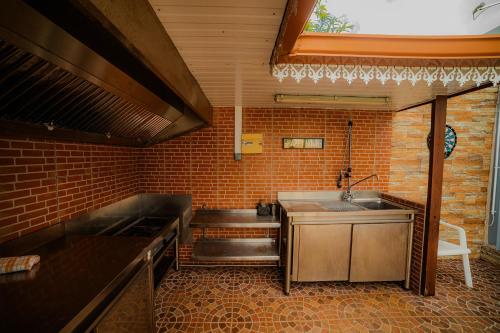 a kitchen with a sink and a brick wall at Lilie location sud in Petite Île