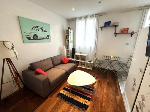 een woonkamer met een bank en een tafel bij Studio lumineux aux portes de Paris in Clichy